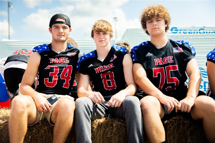 Three boys wearing football jerseys smile